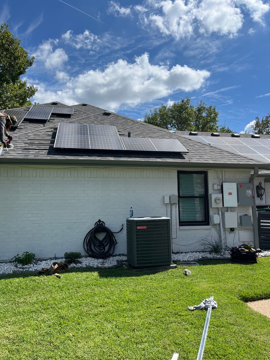 Roof installation of solar panels with HVAC unit in a residential setting on a sunny day.