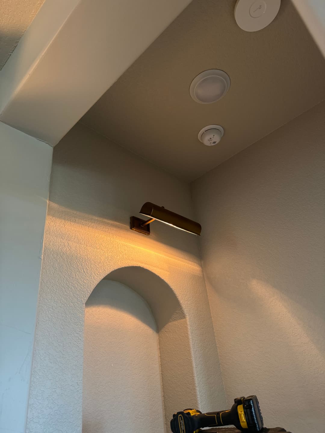 Corner wall with a modern light fixture and ceiling sensors, highlighting a textured background.