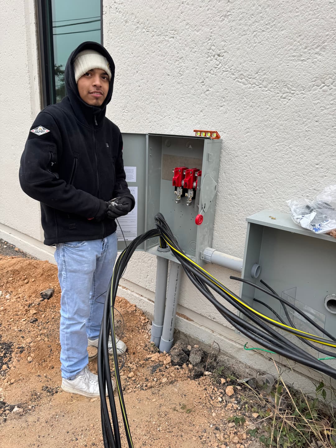 Electrician working on outdoor electrical connections with cables and equipment.