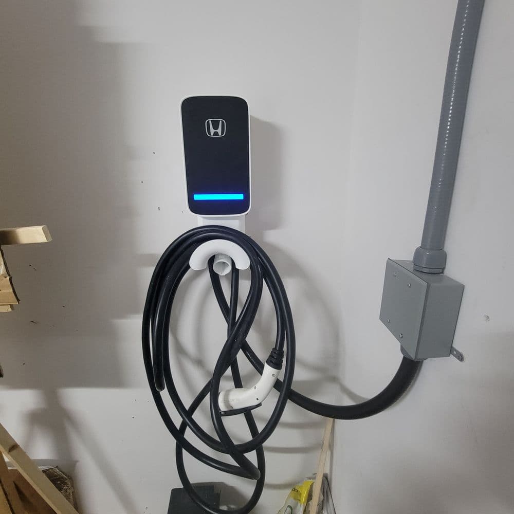 Honda electric vehicle charging station mounted on wall with charging cable coiled.