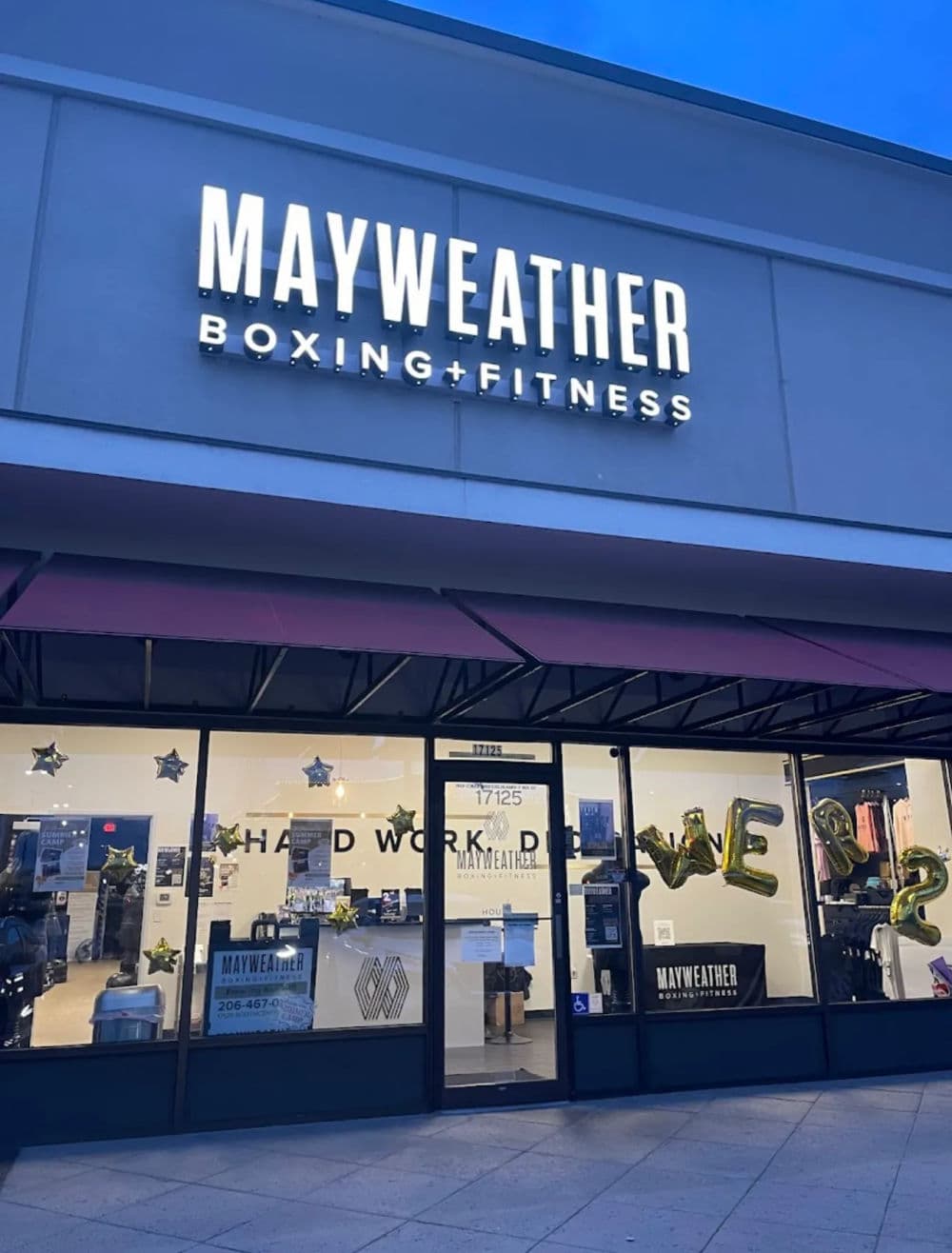 Mayweather Boxing + Fitness storefront with illuminated sign and celebratory decorations.