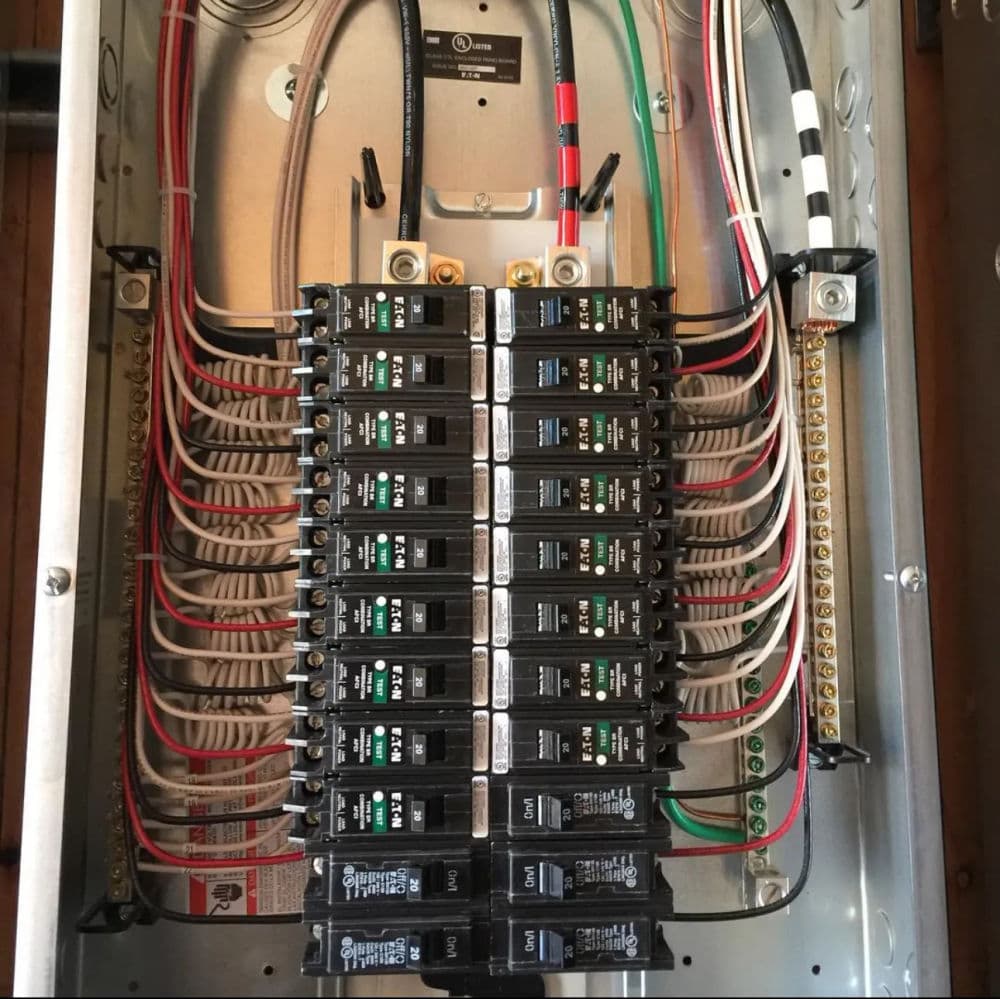 Electrical panel with multiple circuit breakers and wiring, neatly organized and labeled.