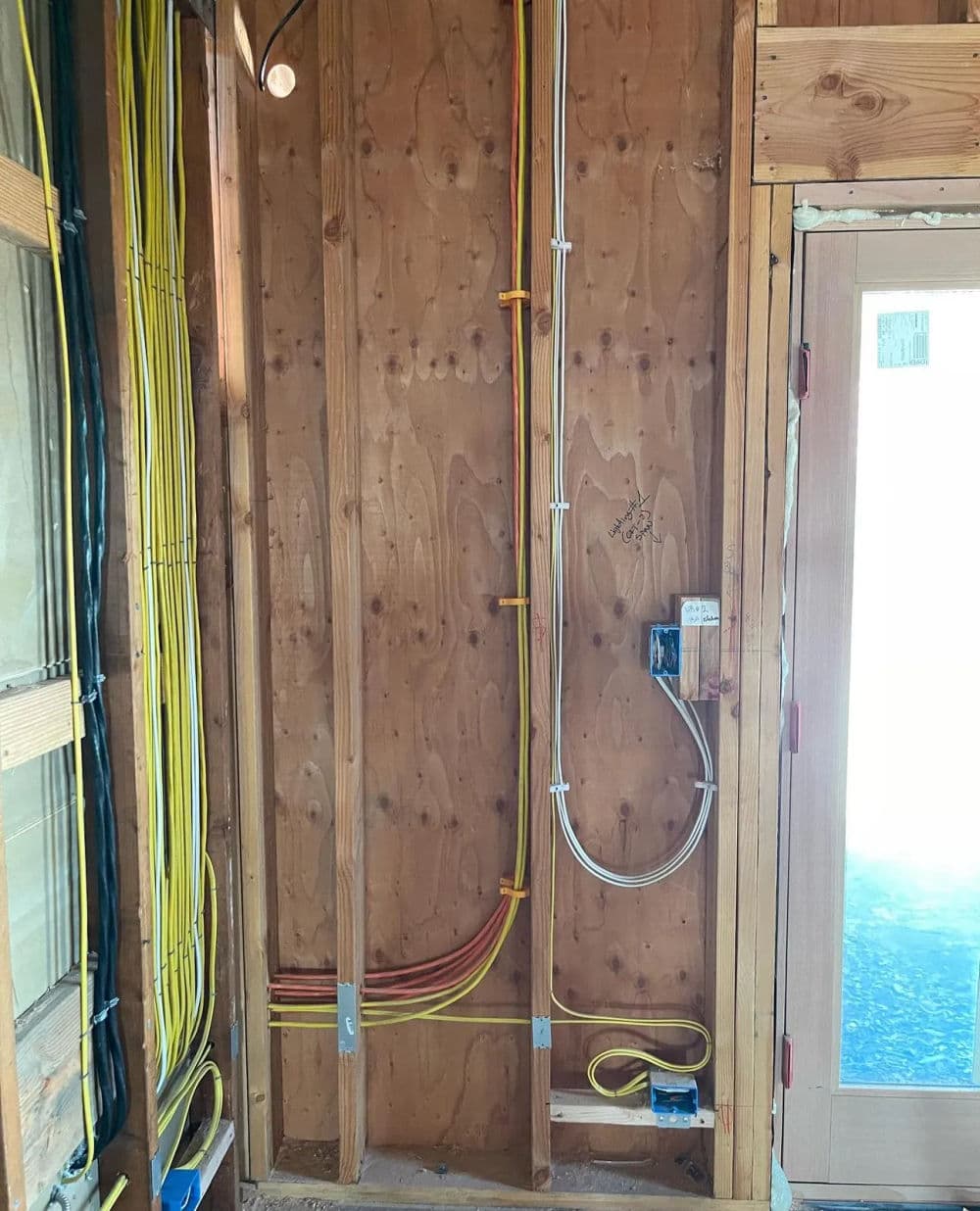 Exposed wooden wall with electrical wiring and conduit installation during home renovation.