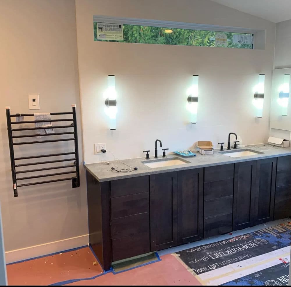Modern bathroom with dual sinks, wall-mounted lights, and towel warmer.